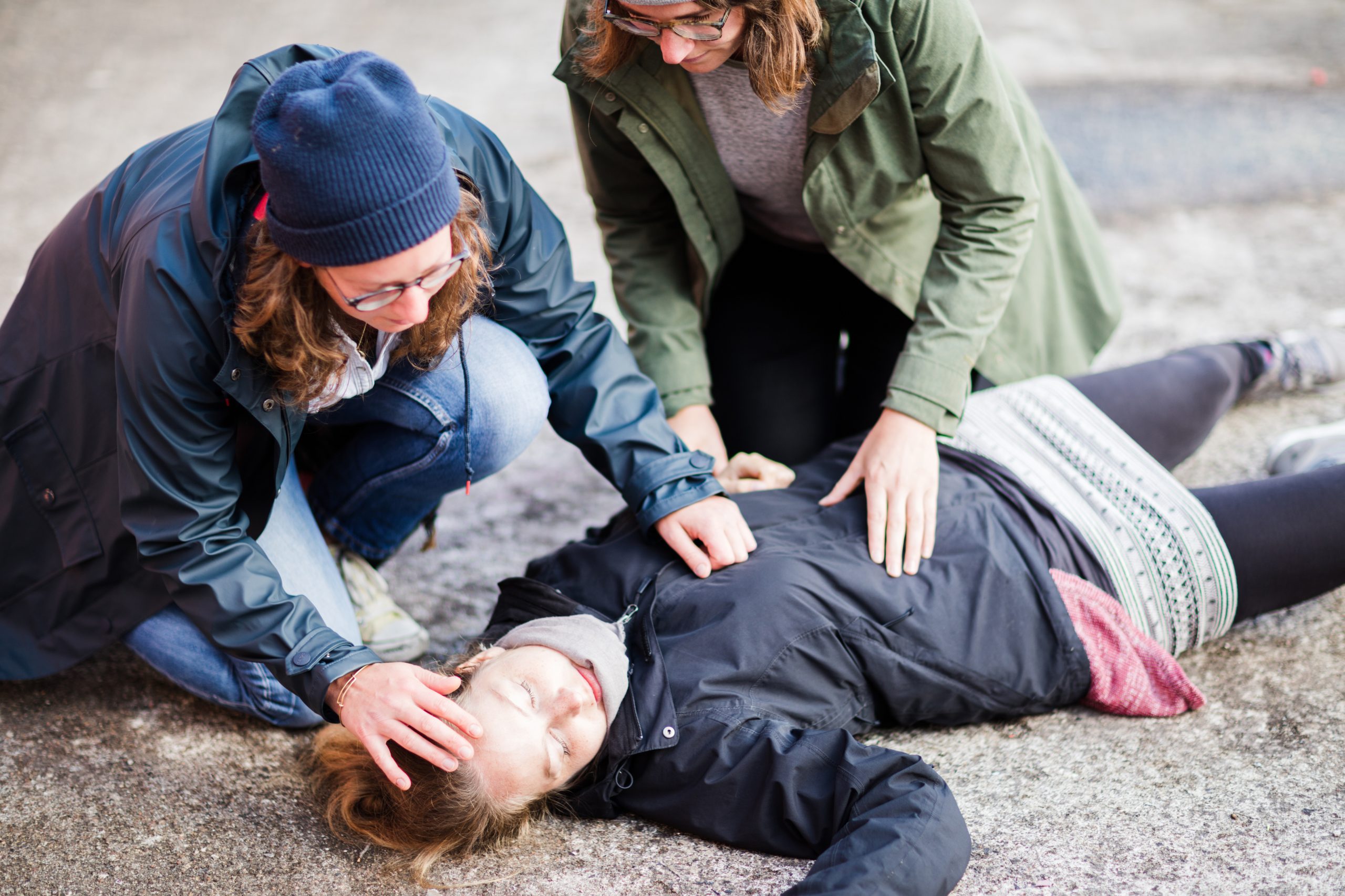 Two woman looking after unconscious woman